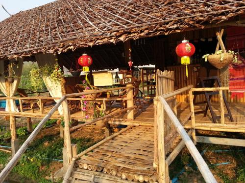 a wooden house with a thatched roof and a wooden bench at Tulip Resort Pai in Pai