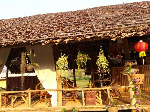a house with a thatched roof with potted plants at Tulip Resort Pai in Pai