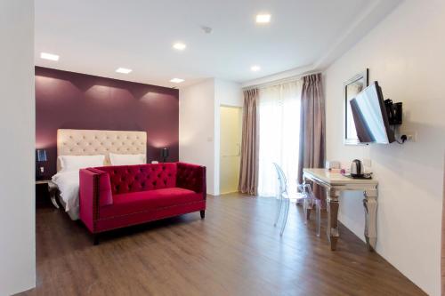 a bedroom with a red chair and a bed at Aloha Hotel SDN BHD in Pontian Kecil