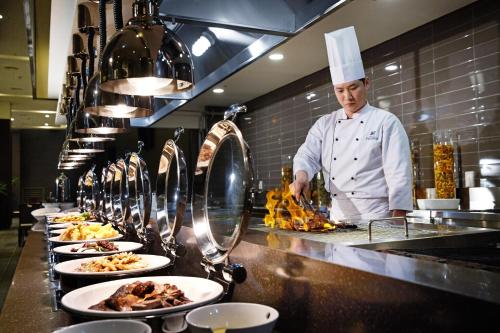 a chef standing in a kitchen with plates of food at Hotel Prumir in Hwaseong