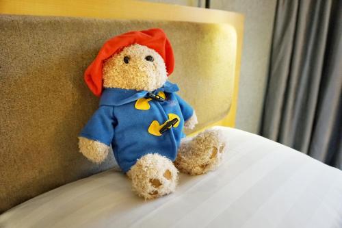 a stuffed teddy bear sitting on a bed at Kew Green Hotel Wanchai Hong Kong in Hong Kong