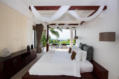 een slaapkamer met een groot wit bed en een tafel bij Baan Phukhao in Klong Muang Beach