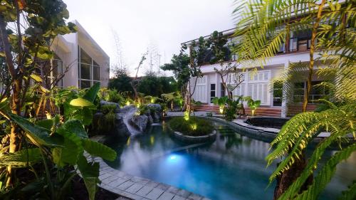 a swimming pool in a garden with a waterfall at YATS Colony in Yogyakarta