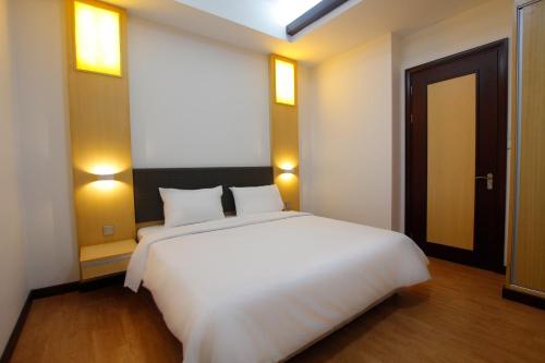 a large white bed in a room with a door at Imperial Suites Miri , Diamond Tower in Miri