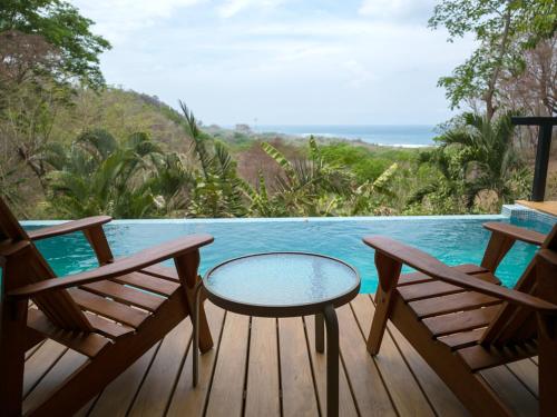 a deck with two chairs and a table and a pool at Casa Chameleon Hotel Mal Pais - Adults Only in Santa Teresa Beach