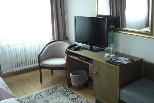 a room with a tv and a desk with a chair at Hotel Solinger Hof in Solingen