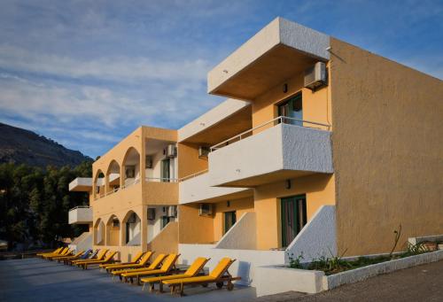 un bâtiment avec une rangée de chaises devant lui dans l'établissement Anthi Maria Beach Apartments, à Pefki