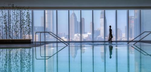 a person standing in a pool looking at the city at Four Seasons Hotel Tianjin in Tianjin