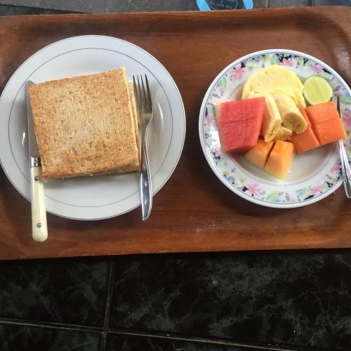 a wooden tray with two plates of food with fruit and toast at Bagus Homestay in Ubud
