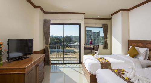 a bedroom with two beds and a flat screen tv at Airport Resort Phuket in Nai Yang Beach