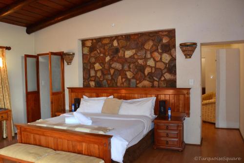 Un dormitorio con una cama grande con una pared de piedra. en La Montagne Guest Lodge, en Hartbeespoort