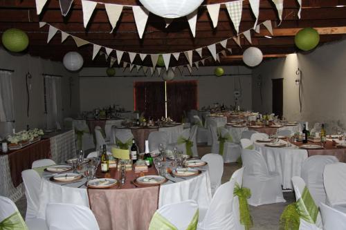 a banquet hall with white tables and white chairs at Intaba Lodge in Elliot
