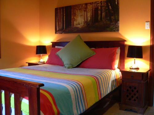 a bedroom with a bed with colorful sheets and two lamps at Lantauanan - The Lookout in Island Beach