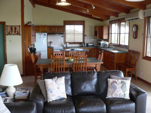 a living room with a leather couch and a kitchen at Lantauanan - The Lookout in Island Beach