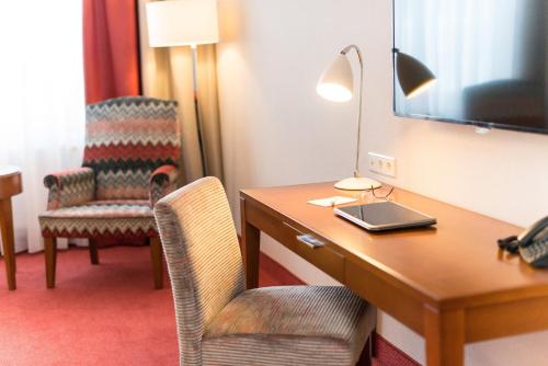 a hotel room with a desk with a lamp and chairs at Best Western Plus Hotel St. Raphael in Hamburg