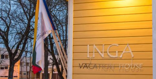 a yellow house with a flag next to a building at Inga Vacation House in Druskininkai