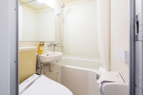 W łazience znajduje się umywalka, toaleta i lustro. w obiekcie Flexstay Inn Sakuragicho w mieście Jokohama