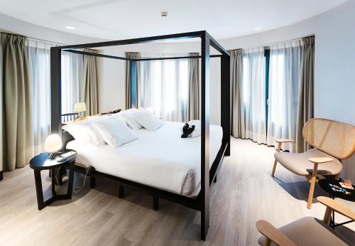 a bedroom with a black and white bed and windows at One Shot Luchana in Madrid