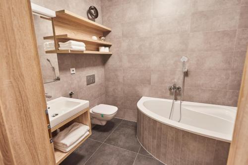 een badkamer met een bad, een toilet en een wastafel bij Apartmány Volarik in Mikulov
