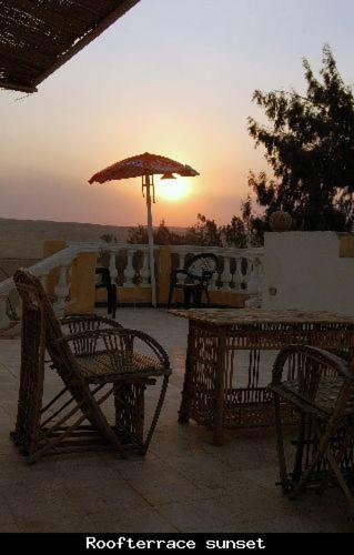 a patio with two chairs and an umbrella at Sakkara pyramid inn hotel in Cairo