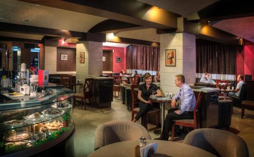 a group of people sitting at tables in a restaurant at Voyage Hotel in Almaty