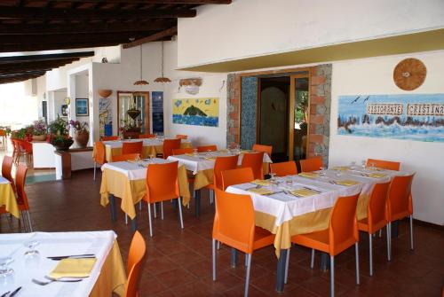 a restaurant with white tables and orange chairs at Hotel Cristina in Diamante