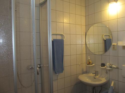 a bathroom with a sink and a shower with a mirror at Pension Mahrets Puppenstube in Eisenach