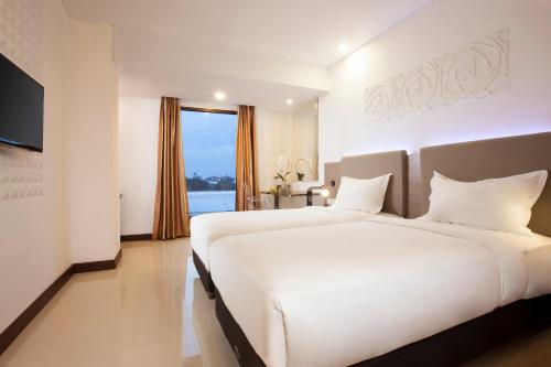 a hotel room with two beds and a television at Verse Hotel Cirebon in Cirebon