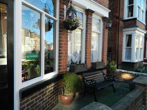 a bench in front of a brick building with windows at The George Guest House in Bridlington