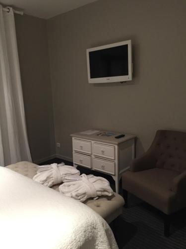 a hotel room with a bed and a chair and a tv at Hotel Le Clos De La Prairie in Gouy-Saint-André