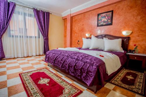 Appart Hotel Les Ambassadeurs في مراكش: غرفة في الفندق مع سرير كبير مع ملاءات أرجوانية