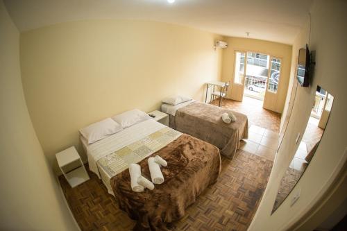 a small bedroom with two beds and a television at Hotel Pedra Bonita in Camaquã