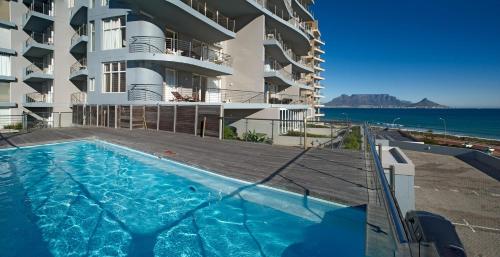 a swimming pool in front of a building with the ocean at Horizon Bay 1404 in Bloubergstrand