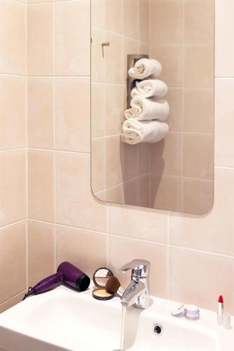 une salle de bain avec un lavabo, un miroir et des serviettes dans l'établissement Hôtel Le Saint Germain, à Aulnay-sous-Bois