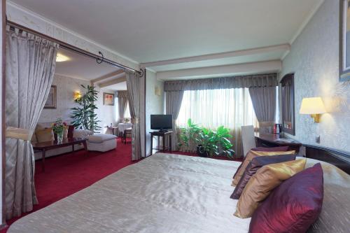 a bedroom with a large bed and a living room at Capitol Hotel in Varna City