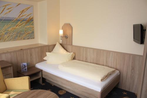 a small room with a bed and a chair at Hotel Seeterrassen in Laboe