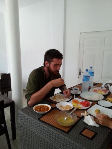 a man sitting at a table eating food at Mama Beach Villa in Negombo