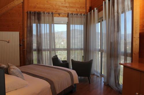 a bedroom with a bed and a large window at Hôtel Restaurant Les Alisiers in Lapoutroie