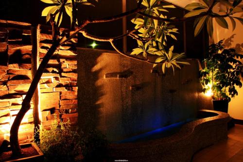 a garden with a stone wall and a tree with lights at Huang Xing Motel in Pingtung City