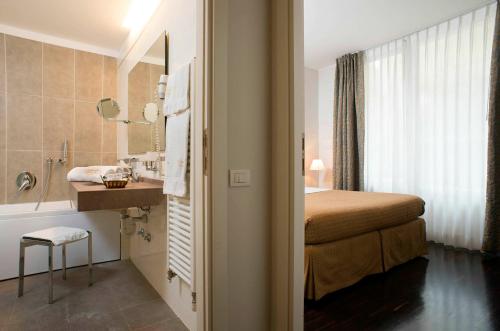 リミニにあるVilla dei Gelsomini & National Hotel dal 1903のバスルーム(ベッド1台、シンク、バスタブ付)