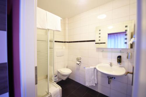 a white bathroom with a toilet and a sink at Hotel Dolce Vita in Bernkastel-Kues