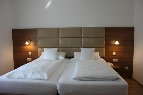 a bedroom with two beds with white sheets and lights at Hotel Rheinbrücke in Rheinfelden