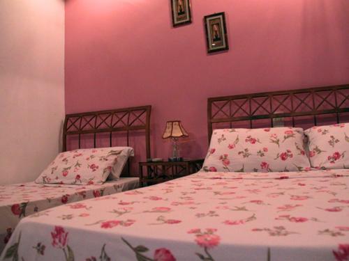 two beds in a bedroom with pink walls at Pousada Requinte in Vila Velha