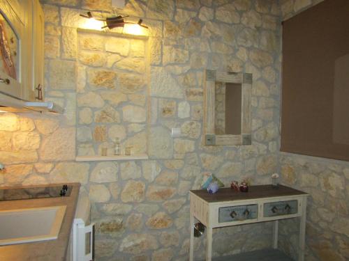 a bathroom with a stone wall with a table and a mirror at Villa Lydia in Meganisi