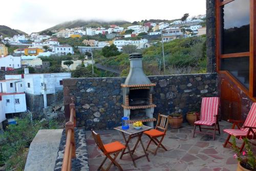 un patio con mesa, sillas y chimenea en Casa Rural El Hondillo en Valverde