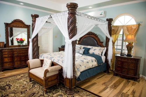 a bedroom with a canopy bed and a chair at Villa Sweet Villa - Montego Bay in Montego Bay