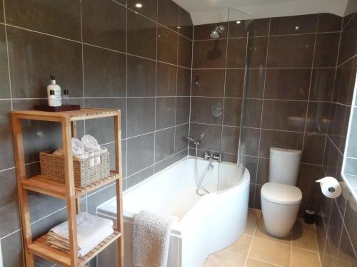 a bathroom with a bath tub and a toilet at Coach House at The Glen in Helensburgh