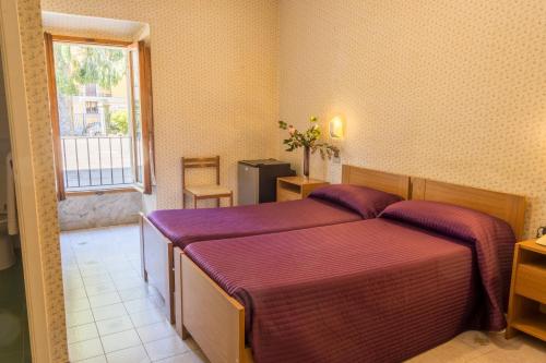 - une chambre avec 2 lits avec des draps violets et une fenêtre dans l'établissement Hotel Italia Abbadia, à Abbadia San Salvatore