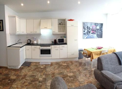 - une cuisine avec des placards blancs, une table et un canapé dans l'établissement Appartement Au Coeur de Liege, à Liège
