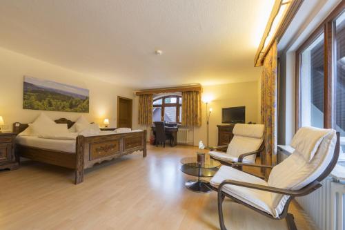 a bedroom with a bed and a living room at RelaxHotel Tannenhof in Sasbachwalden